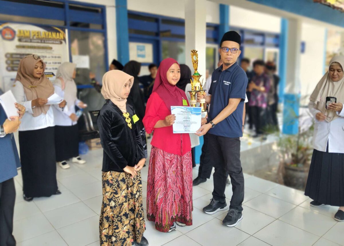 Kepala Bidang SD Dinas Pendidikan Kabupaten Sampang, Yusuf, menyerahkan piala dan piagam kepada salah satu pemenang lomba Festival Tunas Bahasa Ibu 2026 di pelataran gedung SMPN 4 Sampang, pada Rabu (30/9/2026) FOTO: Acung/RADAR EXPOSE.