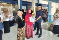 Kepala Bidang SD Dinas Pendidikan Kabupaten Sampang, Yusuf, menyerahkan piala dan piagam kepada salah satu pemenang lomba Festival Tunas Bahasa Ibu 2026 di pelataran gedung SMPN 4 Sampang, pada Rabu (30/9/2026) FOTO: Acung/RADAR EXPOSE.